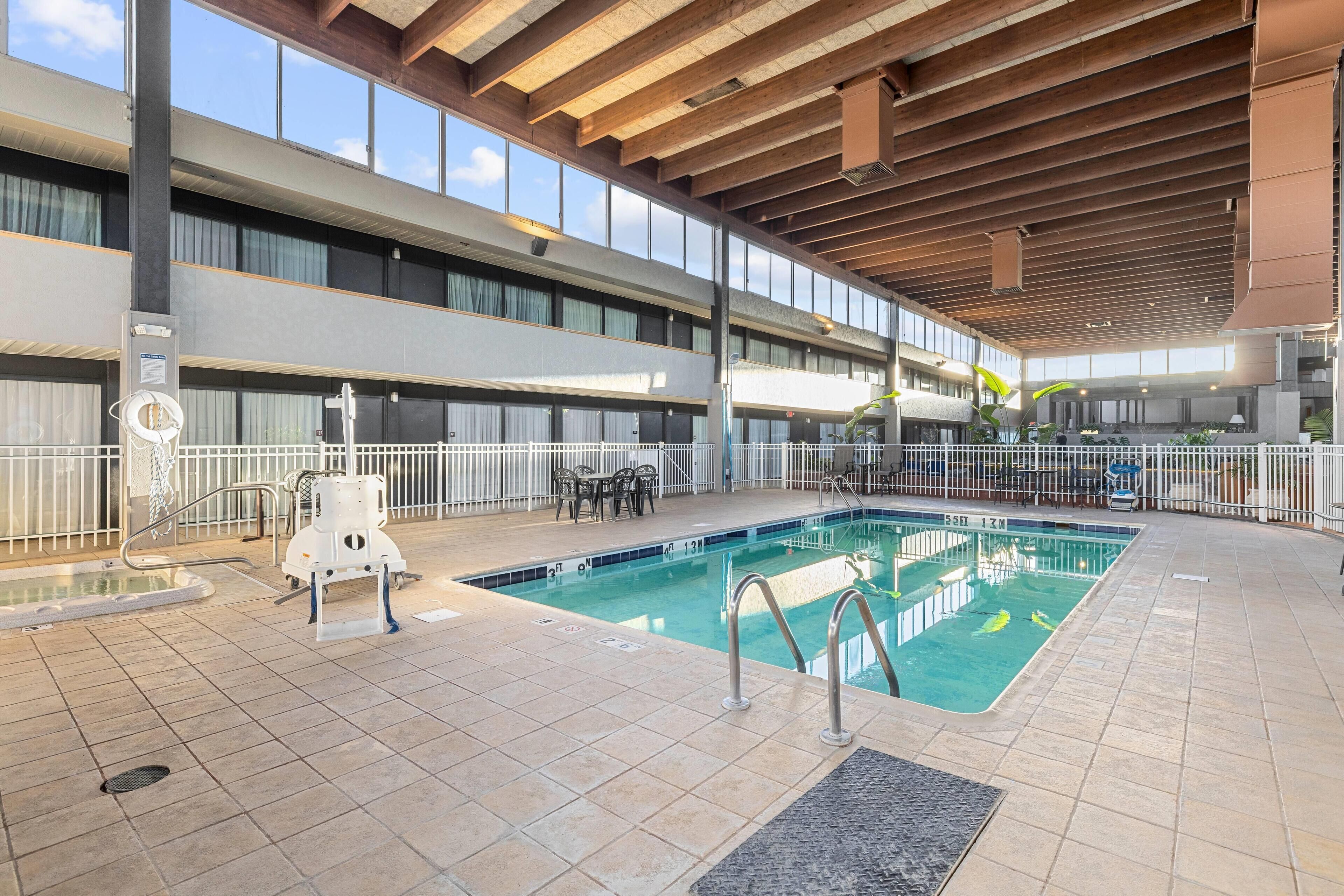 An indoor swimming pool with a tiled floor, a lifeguard chair, and a pool ladder.