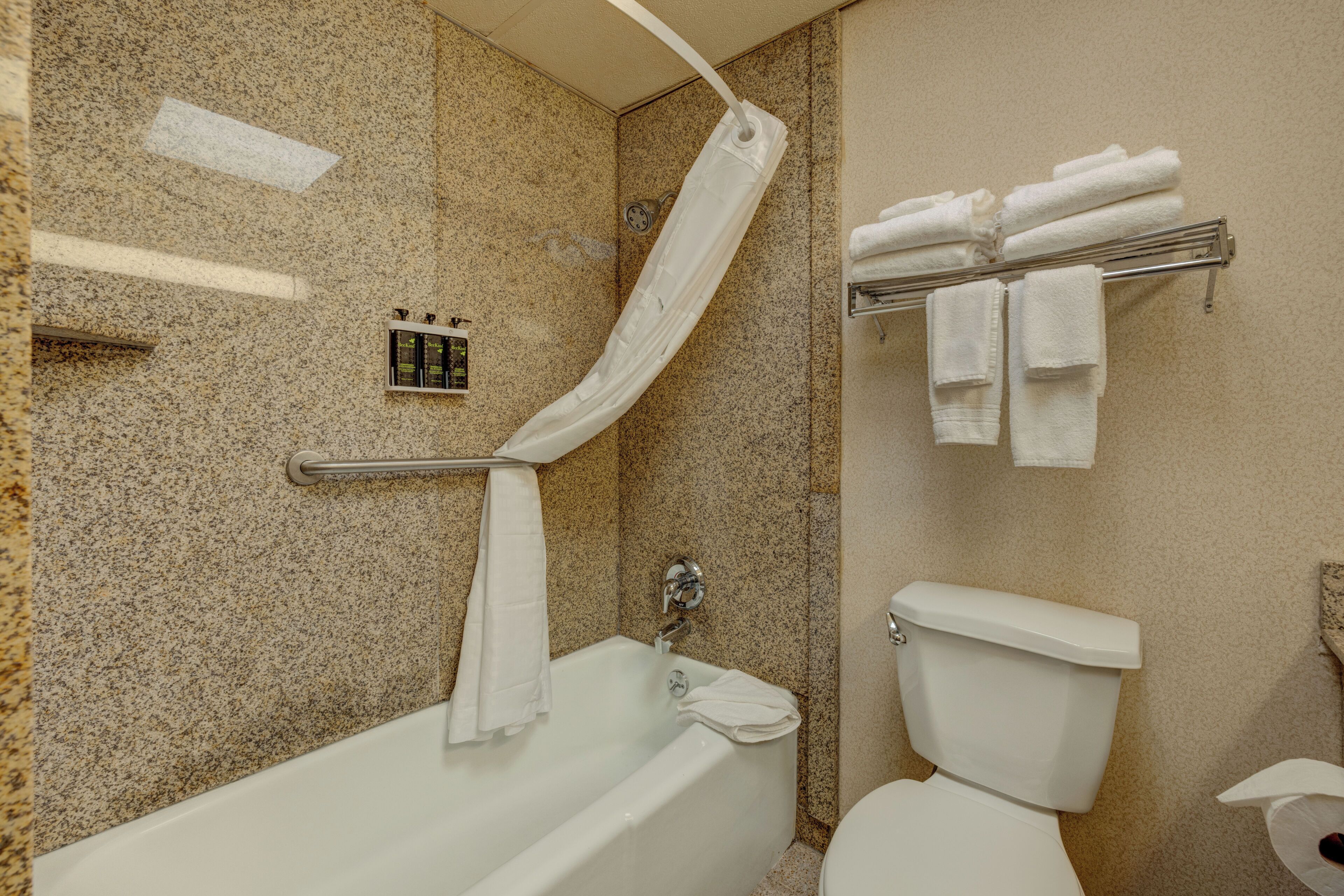 A bathroom with a bathtub, toilet, and towel rack with towels.