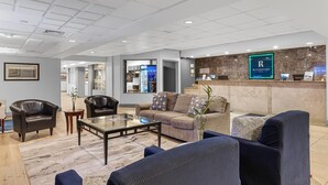 A modern hotel lobby with leather sofas, a glass coffee table, and a reception desk.