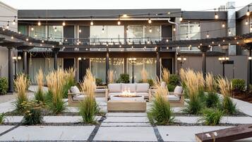 A modern outdoor patio with a fire pit, seating area, and string lights.