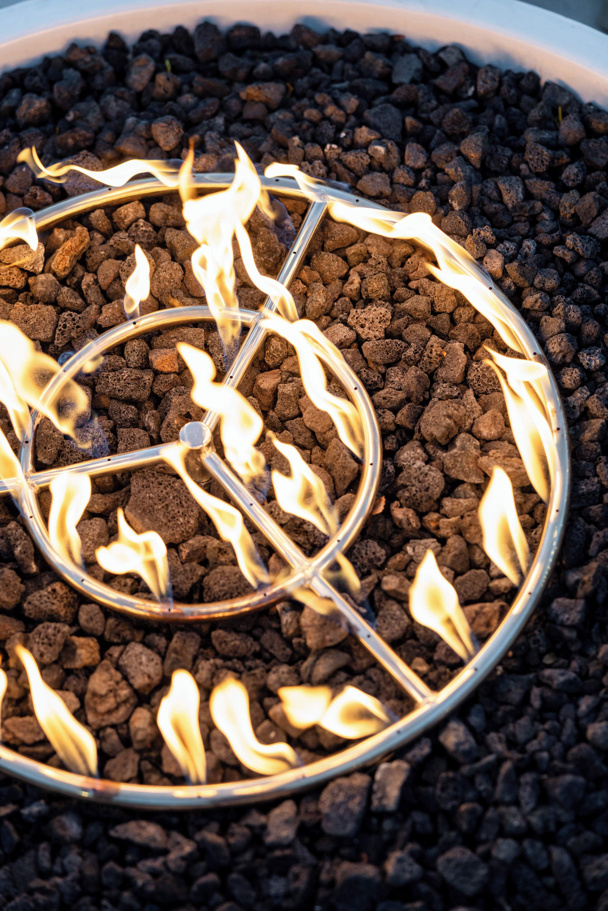 Una estructura metàl·lica circular amb flames a l'interior, envoltada de material fosc i amb textura.