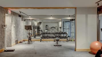 Ein Fitnessraum mit Trainingsgeräten, einer Spiegelwand und einer großen Trainingskugel.