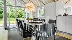 Un espace de salle à manger moderne, doté d’une grande table, de chaises et d’un luminaire suspendu original.