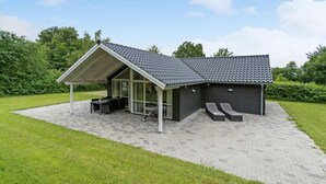 Un espace extérieur moderne, aménagé en patio, avec une table et des chaises pour les repas, un coin salon abrité et une petite piscine.