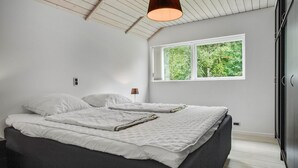 Une chambre à coucher avec un lit, une fenêtre et un luminaire au plafond.