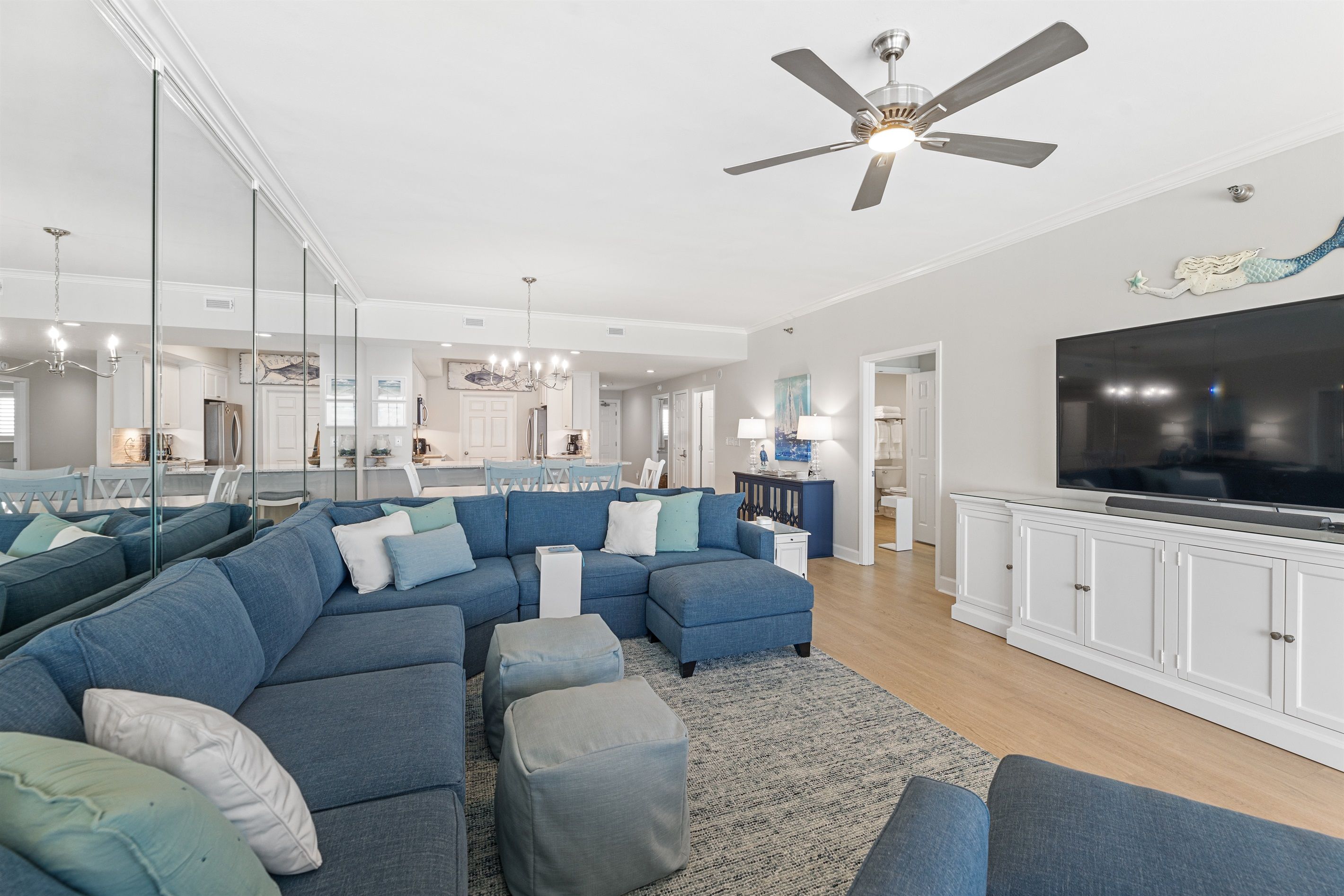 Una sala de estar moderna con un sofá modular, un televisor de pantalla plana y un ventilador de techo.