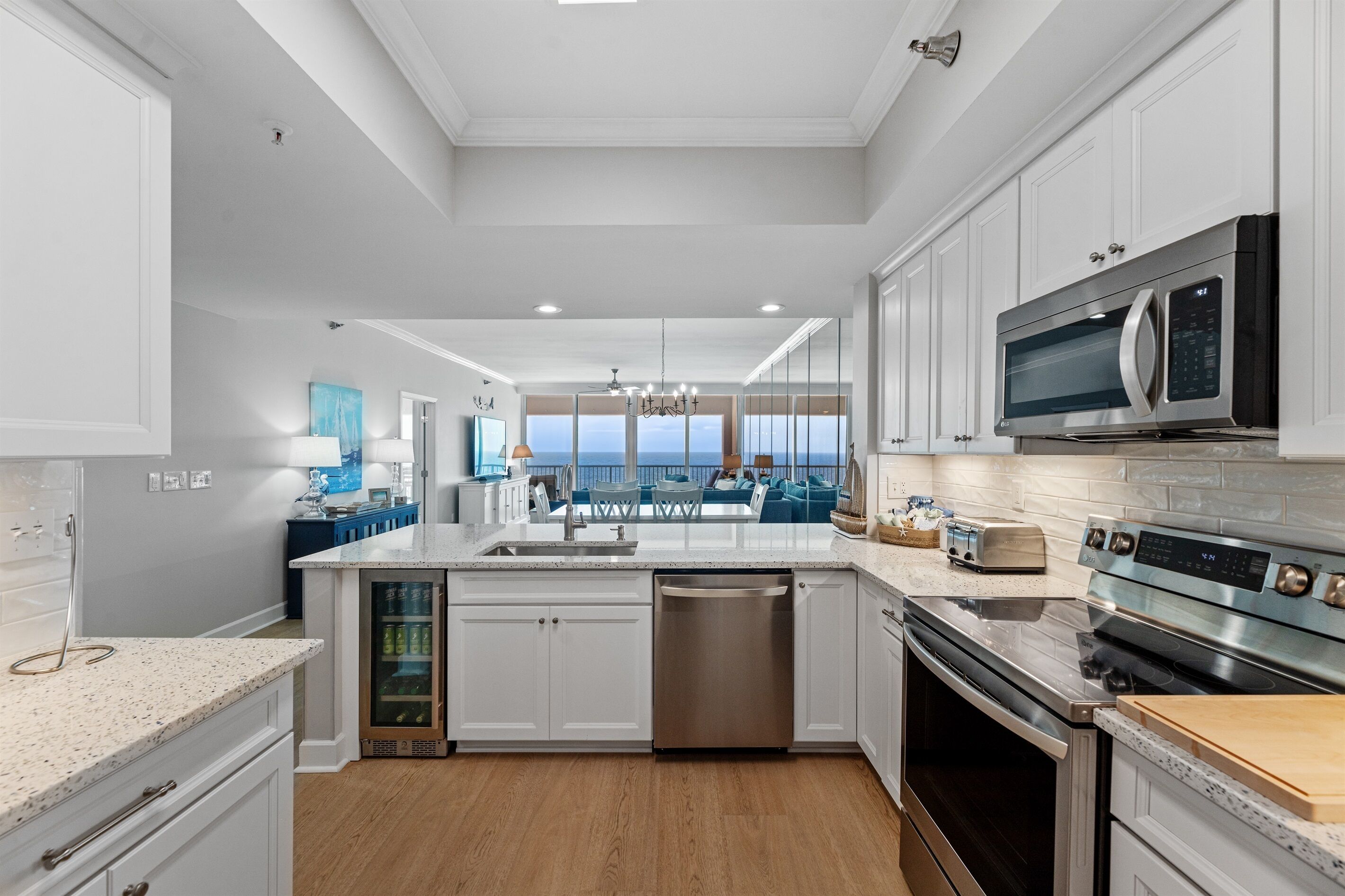 A modern kitchen with white cabinetry, stainless steel appliances, and a view to the outside.