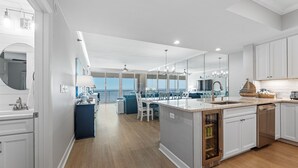 A modern kitchen with a central island, white cabinetry, and a view to the outside. - Salty Breezes (Navarre)