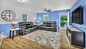 A living room with a sectional sofa, a flat-screen TV, and a ceiling fan.