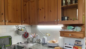 Une cuisine avec des meubles de rangement en bois, un plan de travail en granit, un évier et divers ustensiles de cuisine.