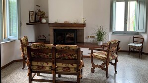 Un salon chaleureux avec une cheminée, des fauteuils à motifs floraux et une grande fenêtre.