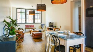 Une cuisine moderne avec un coin repas, de grandes fenêtres et des luminaires suspendus.