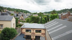 A residential area with houses, some with sloped roofs and others with flat roofs. There are trees and greenery around, and the houses are built on a hillside.