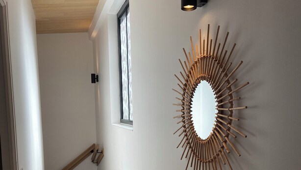 A staircase with wooden steps and a white radiator, leading to a room with a large mirror and a wooden bench.