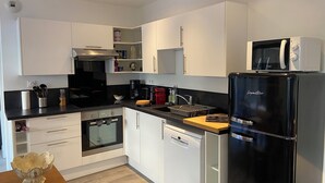 A modern kitchen with white cabinets, a black refrigerator, a microwave, and a dishwasher.