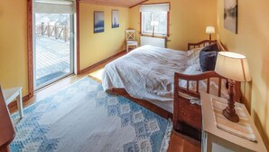 Ein Schlafzimmer mit Bett, Sessel, Nachttisch, Fenster und Blick ins Freie.