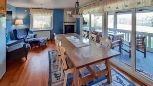 Ein Essbereich mit einem Holztisch und -stühlen, einer blauen Wand, einem Heizkörper und Blick durch große Fenster.