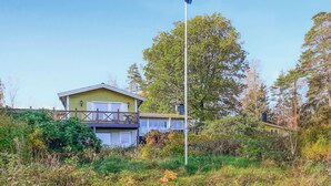 Ein zweistöckiges Haus mit Balkon, umgeben von dichter Vegetation und Bäumen.