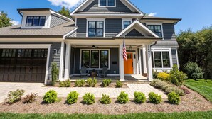 A two-story house with a garage, a covered porch, and a well-maintained front yard. - Glebe Getaway House (Arlington)