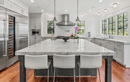 A modern kitchen with a large island, stainless steel appliances, and pendant lighting.