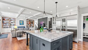 A modern kitchen with grey cabinets, a marble island, stainless steel appliances, and a built-in bookshelf. - Glebe Getaway House (Arlington)