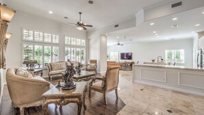 A spacious living area with a high ceiling, large windows, and a central dining table surrounded by chairs. - Tranquil Henderson Retreat with Pool & Spa! (Henderson)