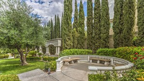 A landscaped garden with a circular bench area, tall cypress trees, and a classical archway. - Tranquil Henderson Retreat with Pool & Spa! (Henderson)