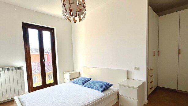 Un dormitorio con cama, mesita de noche, armario y ventana con vistas.