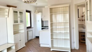 Una cocina con armarios blancos, un refrigerador, un lavamanos y una ventana.