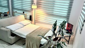A modern bedroom with a bed, bedside table, lamp, and a TV on a stand.