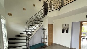A spacious interior with a black and white staircase, a wooden door, and a bench.