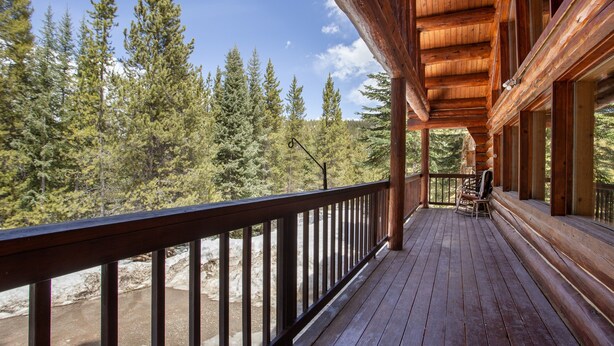 A wooden deck with a railing overlooking a forested area. - Great Condo close to the mountain (Breckenridge)