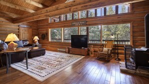A log cabin interior with a television, seating area, and large windows. - Great Condo close to the mountain (Breckenridge)