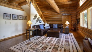 A log cabin interior with a wooden staircase, leather sofas, a patterned rug, and framed pictures on the walls. - Great Condo close to the mountain (Breckenridge)