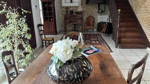 Une table à manger avec un vase de fleurs, un buffet en bois et un escalier en arrière-plan.
