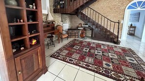 Un vaste espace de vie comprenant un meuble en bois, un tapis à motifs, un escalier et une vue sur l’extérieur.