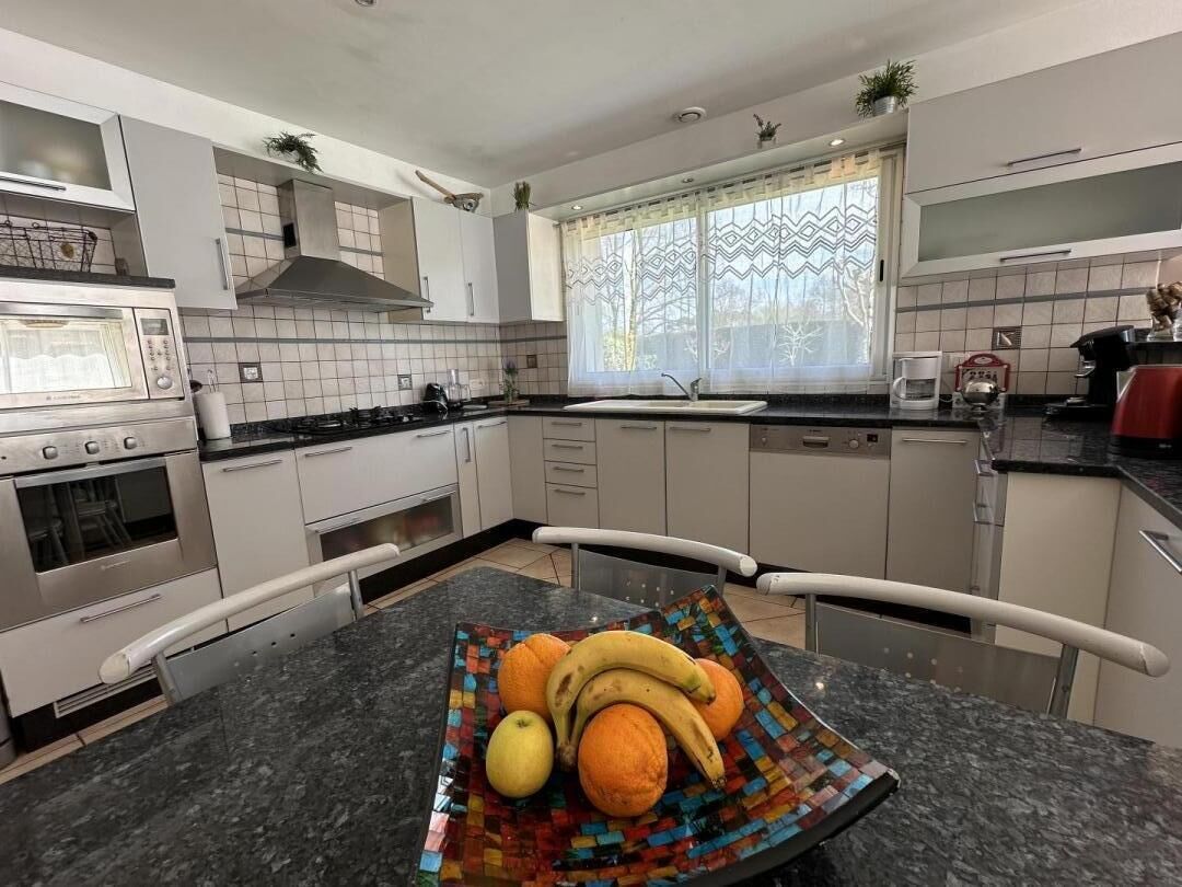 Une cuisine moderne avec des armoires blanches, un plan de travail en granit, un four à micro-ondes, une cuisinière et un évier.