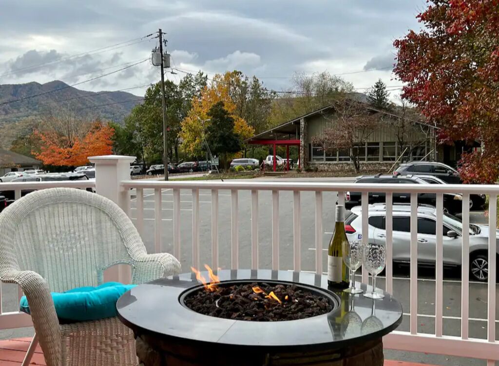 Un balcon avec un foyer, une chaise et une bouteille de vin.
