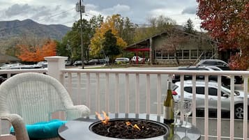 A balcony with a fire pit, a chair, and a bottle of wine.