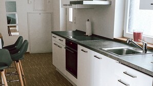 Une cuisine moderne avec des armoires blanches, un évier en acier inoxydable et un plancher en bois.