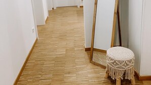 Un couloir doté d’un plancher en bois, de murs blancs et d’un grand miroir appuyé contre un mur.
