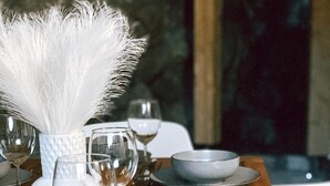 Une table en bois, agrémentée de centres de table blancs ornés de plumes, de verres à vin en verre transparent, ainsi que d’assiettes et de bols gris.