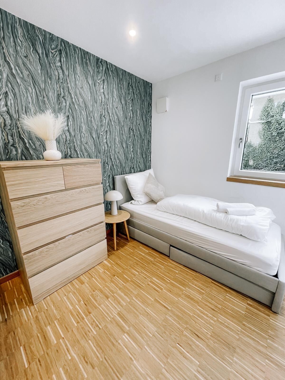 Un dormitorio moderno con una cama, un aparador de madera y una pared con diseño de mármol.