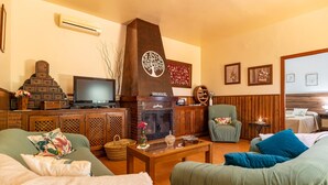 Un salon chaleureux avec une cheminée, un téléviseur et des fauteuils confortables.