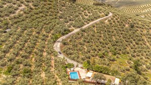Une vue aérienne d’une propriété comprenant une route sinueuse, une piscine et un petit bâtiment.