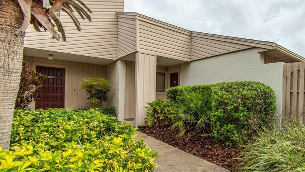 A building with a beige exterior, a front door, and a small porch area. - TimeOut 2!  Spacious 2 bed/2bath condo, Sleeps 6, Pool! (Mulberry)