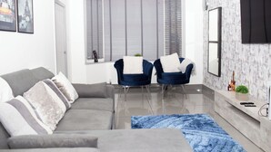 A modern living room with a grey sofa, two blue armchairs, a blue rug, and a large window with blinds. - The Grey Mansion near Manchester City Stadium, Co-Ops LIVE, Piccadilly... (Manchester)
