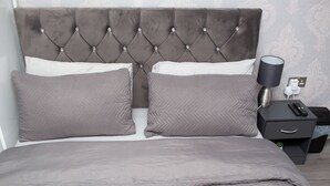 A neatly made bed with a tufted headboard, a bedside table with a lamp, and a power outlet. - The Grey Mansion near Manchester City Stadium, Co-Ops LIVE, Piccadilly... (Manchester)