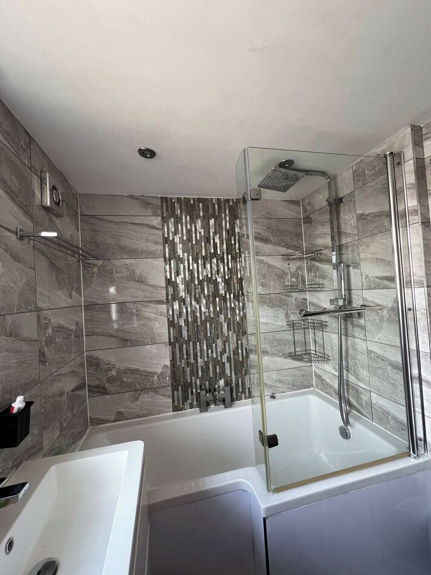 Une salle de bain moderne avec une douche à parois de verre, une baignoire blanche et un meuble-lavabo avec un miroir.