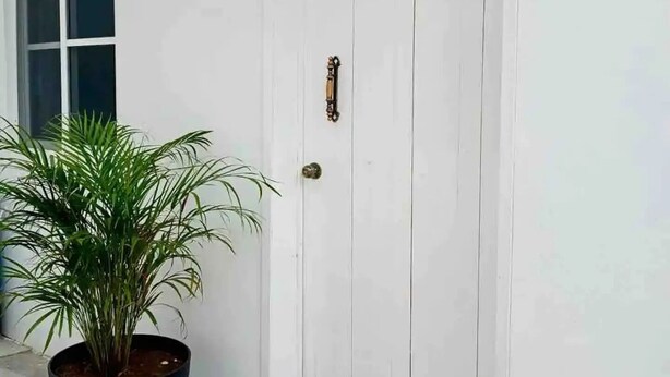 Una porta blanca amb una nansa de bronze i una petita finestra a la part superior.